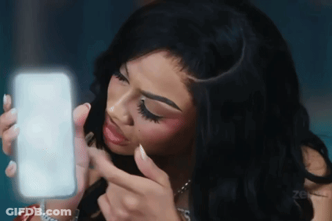 A Woman Is Looking At Herself In The Mirror GIF