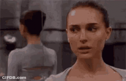 A Woman Is Looking At Herself In The Mirror . GIF