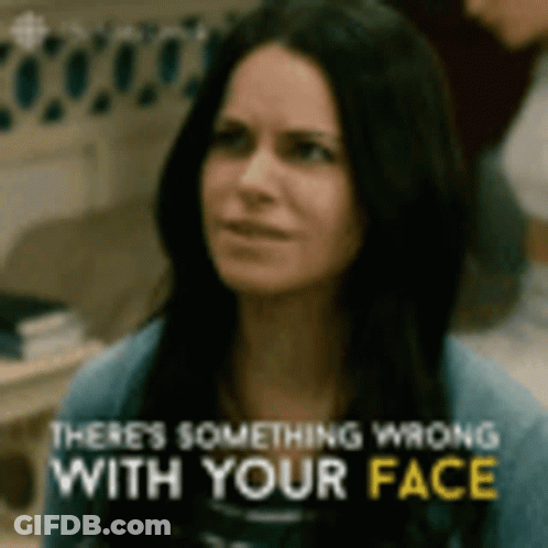 A Woman Is Looking At The Camera With The Words `` There 'S Something Wrong With Your Face '' Written Above Her . GIF