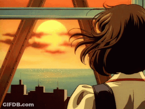 A Woman Is Looking Out A Window At The Sun Setting Over The Ocean GIF