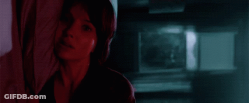 A Woman Is Looking Out A Window With A Blue Sky In The Background . GIF