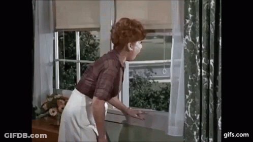 A Woman Is Looking Out Of A Window . GIF