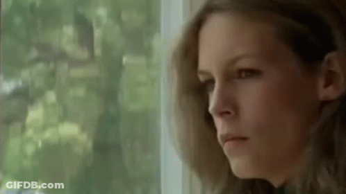A Woman Is Looking Out Of A Window And Making A Serious Face . GIF