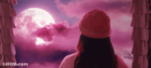 A Woman Is Looking Out Of A Window At A Full Moon . GIF