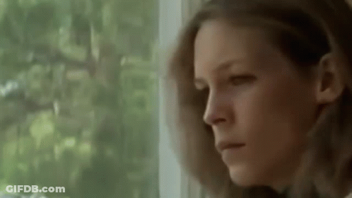 A Woman Is Looking Out Of A Window With A Serious Look On Her Face . GIF