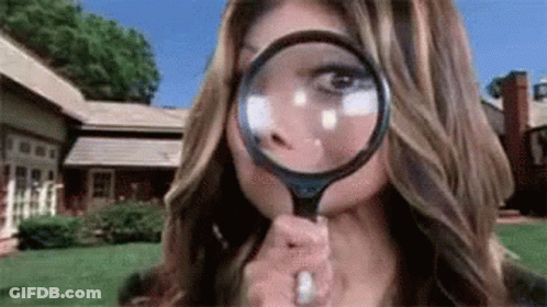 A Woman Is Looking Through A Magnifying Glass To Her Face . GIF
