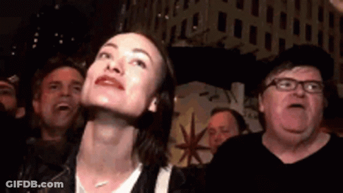 A Woman Is Looking Up At Something While A Man Looks Down At Her . GIF