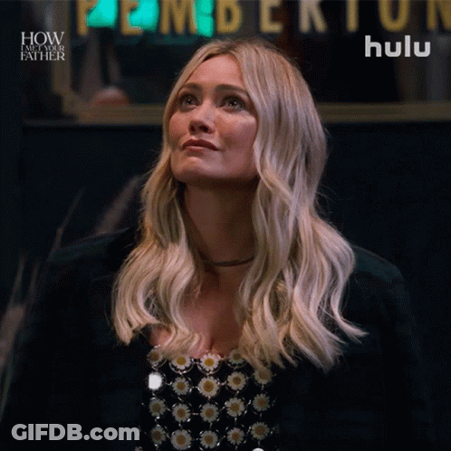 A Woman Is Looking Up In Front Of A Hulu Sign GIF