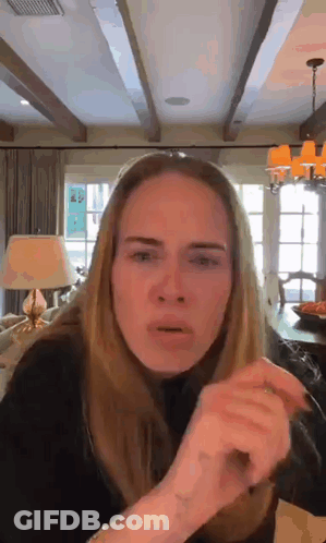 A Woman Is Making A Funny Face In A Living Room With A Lamp . GIF