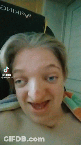 A Woman Is Making A Funny Face In Front Of A Chair That Says Warpach 2.0 GIF