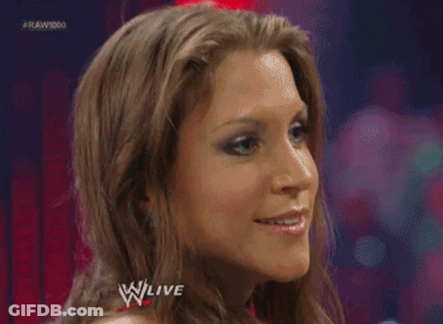 A Woman Is Making A Funny Face In Front Of A Sign That Says W Live GIF