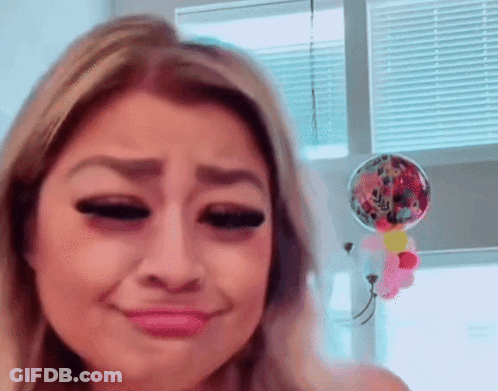 A Woman Is Making A Funny Face In Front Of A Window With Balloons Hanging From It . GIF