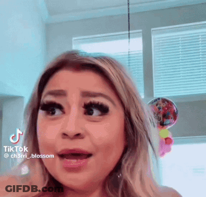 A Woman Is Making A Funny Face In Front Of A Window With Balloons In The Background . GIF
