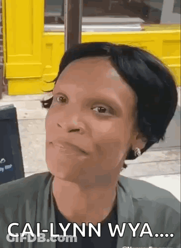 A Woman Is Making A Funny Face In Front Of A Yellow Building And Says Cal-Lynn Wya . GIF
