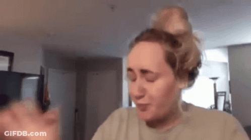 A Woman Is Making A Funny Face While Holding A Cell Phone In A Living Room . GIF