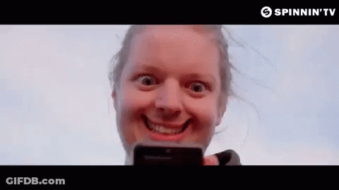 A Woman Is Making A Funny Face While Holding A Cell Phone In Her Hand . GIF