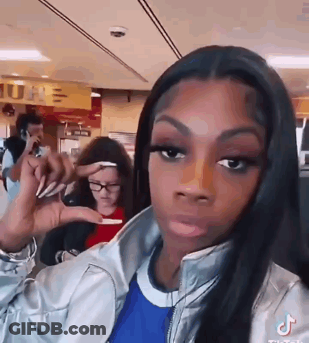 A Woman Is Making A Funny Face While Holding Something In Her Hand In A Restaurant . GIF