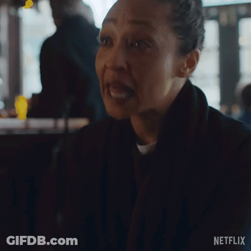 A Woman Is Making A Funny Face While Sitting At A Table In A Bar . GIF