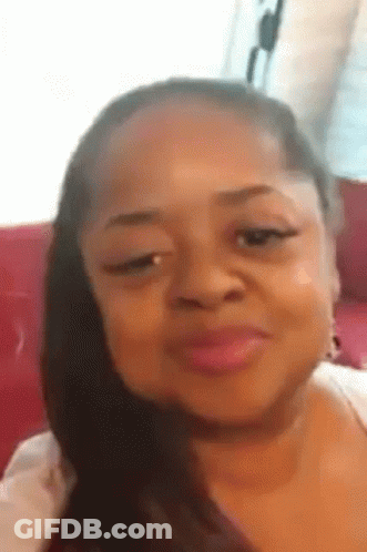 A Woman Is Making A Funny Face While Sitting On A Red Couch . GIF