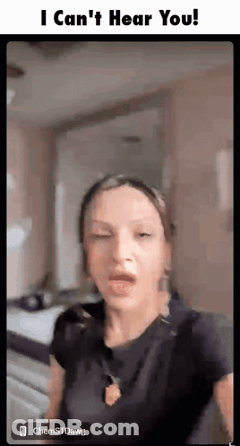 A Woman Is Making A Funny Face While Standing In A Room With Her Eyes Closed . GIF