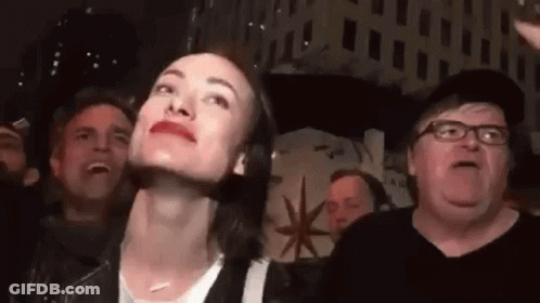 A Woman Is Making A Funny Face While Standing In Front Of A Crowd Of People . GIF