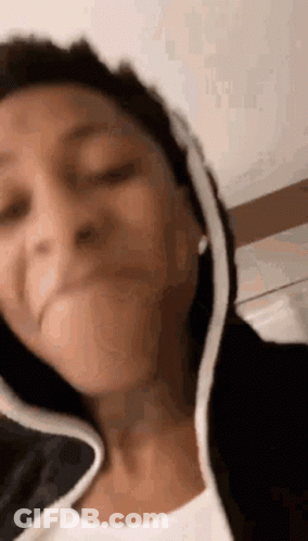 A Woman Is Making A Funny Face While Wearing A Hoodie . GIF