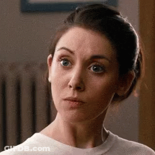 A Woman Is Making A Funny Face While Wearing A White Shirt . GIF