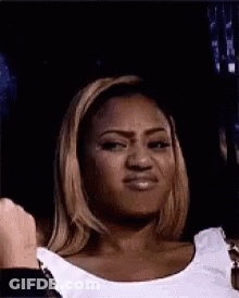 A Woman Is Making A Funny Face While Wearing A White Tank Top . GIF