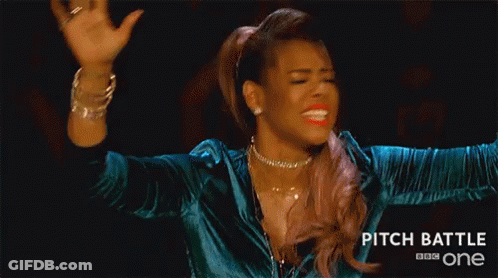 A Woman Is Making A Funny Face With Her Hands In The Air While Wearing A Blue Jacket . GIF