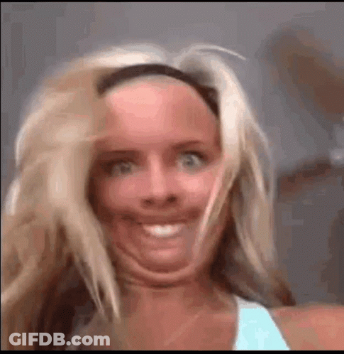 A Woman Is Making A Funny Face With Her Mouth Open And Her Hair Blowing In The Wind . GIF