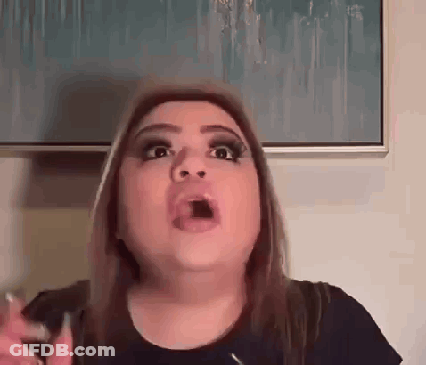 A Woman Is Making A Funny Face With Her Mouth Open In Front Of A Picture . GIF