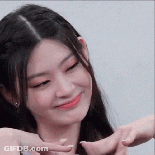 A Woman Is Making A Heart Shape With Her Hands And Smiling . GIF