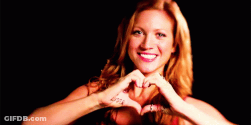 A Woman Is Making A Heart Shape With Her Hands In Front Of Her Face . GIF