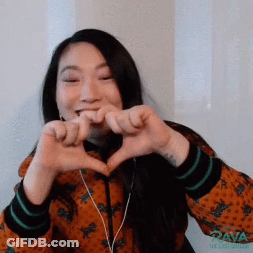 A Woman Is Making A Heart With Her Hands While Wearing Headphones . GIF
