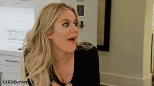 A Woman Is Making A Surprised Face In A Kitchen While Wearing A Black Shirt . GIF