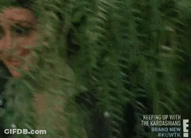 A Woman Is Peeking Out Of A Tree And Smiling . GIF