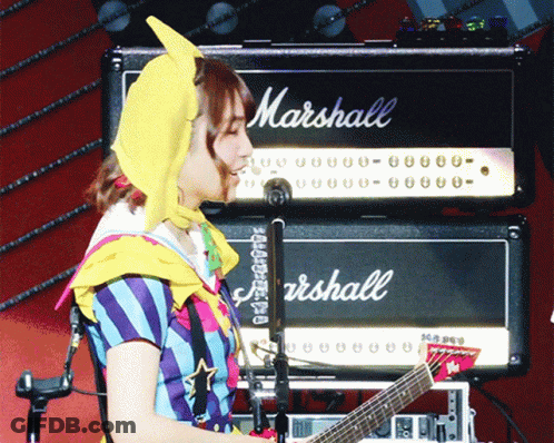 A Woman Is Playing A Guitar In Front Of A Marshall Amp GIF