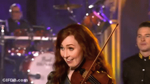 A Woman Is Playing A Violin In Front Of A Drum Set That Says Dw GIF