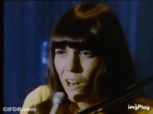 A Woman Is Playing A Violin In Front Of A Microphone . GIF