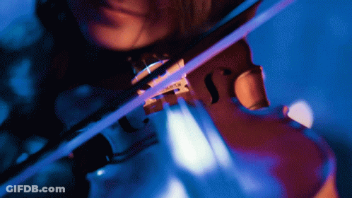 A Woman Is Playing A Violin With A Blue Light Behind Her GIF