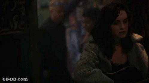 A Woman Is Playing An Acoustic Guitar In A Dark Room . GIF