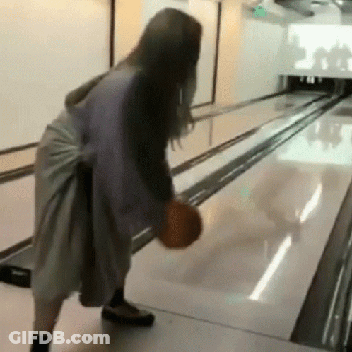 A Woman Is Playing Bowling With A Bowling Ball . GIF