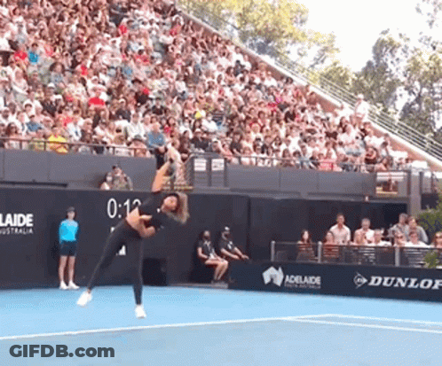 A Woman Is Playing Tennis In Front Of A Crowd And A Sign That Says Adelaide GIF
