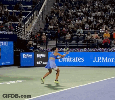 A Woman Is Playing Tennis In Front Of A Dubai Duty Free Banner GIF