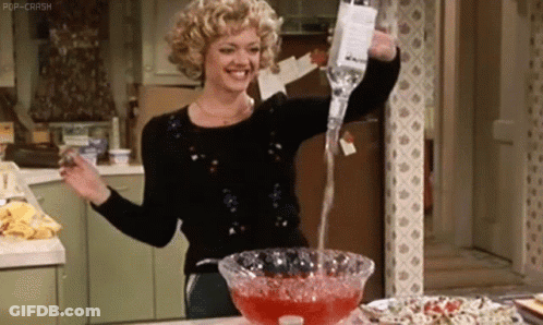 A Woman Is Pouring A Drink From A Bottle Into A Glass Bowl . GIF