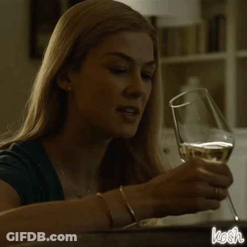A Woman Is Pouring Wine Into A Glass And The Word Kosh Is On The Bottom GIF