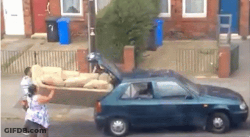 A Woman Is Pushing A Couch In The Back Of A Car . GIF
