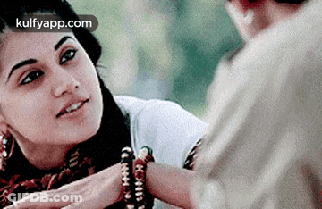 A Woman Is Putting A Bracelet On A Man 'S Wrist And Smiling . GIF