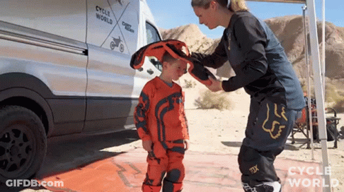 Woman Putting Helmet On Child In Front Of Cycle World Van GIF