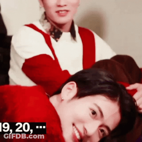 A Woman Is Putting A Red Headband On A Man 'S Head While They Are Sitting On A Couch . GIF